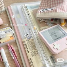 an assortment of stationery items including a gameboy, pens, and pencils