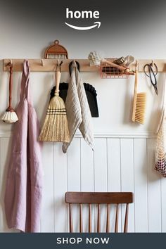 a wooden chair sitting next to a wall with hooks and brooms hanging on it