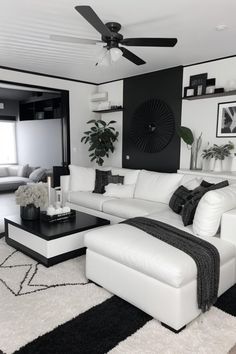 a living room filled with white furniture and black accents on the walls, along with a large rug