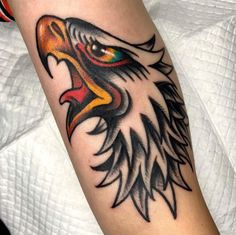 an eagle head tattoo on the arm with colors and black lines around its eyes,