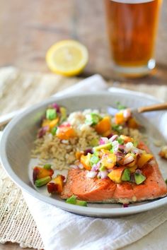 a plate with salmon, rice and vegetables on it next to a glass of beer