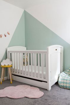 a baby's room with a white crib and pink rug