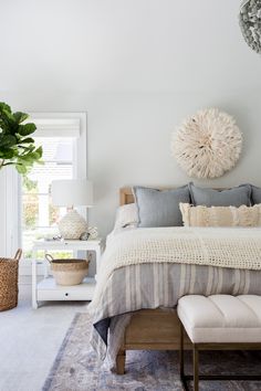 a bedroom with a bed, nightstands and a plant on the wall above it