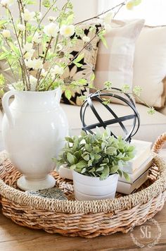 a wicker tray with flowers and books on it in front of a white vase