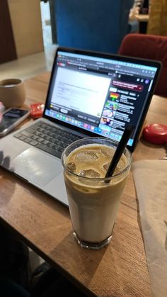 a laptop computer sitting on top of a wooden table next to a cup of coffee