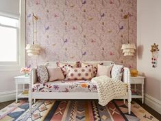 a white day bed sitting on top of a rug next to a window