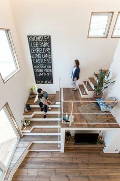 two people are walking up the stairs in a house with wood floors and white walls