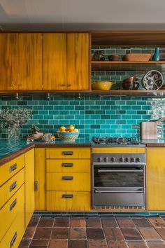 a kitchen with yellow cabinets and green tile backsplashing, including an oven