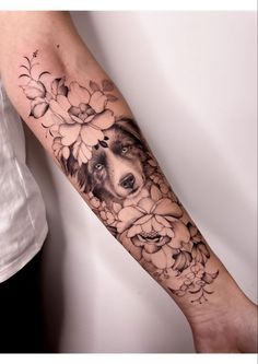 a dog is surrounded by flowers and leaves on this forearm tattoo design, which features a border collie in the center