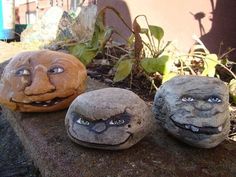 three rocks with faces painted on them sitting next to each other in front of a house