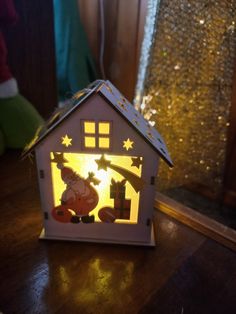 a small house shaped like a christmas scene with a star on the roof and a person holding a lit candle