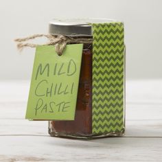 a jar filled with chili paste next to a green tag that says mild chilli paste