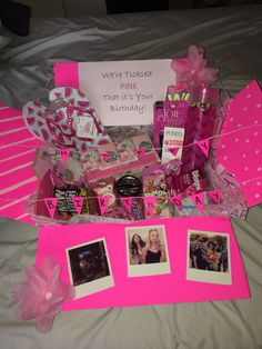 a pink birthday gift box with pictures, cards and other items on top of it