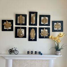 a white fireplace with gold leaf decorations on the mantel and pictures hanging above it