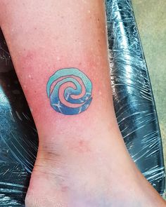 a small tattoo on the foot of a woman's leg with a spiral design