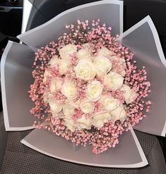 a bouquet of white and pink flowers sitting on top of a car seat