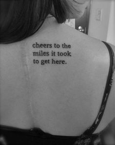 the back of a woman's neck with words on it that say cheers to the miles it took to get here