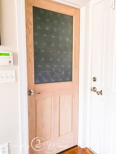 a door with a chalkboard on it in front of a white wall and wooden floor