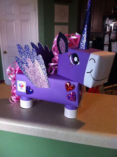 a purple pony made out of toilet paper on top of a counter with pink bows