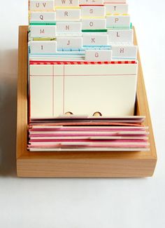 a wooden box with several different types of cards and envelopes in it on a white surface