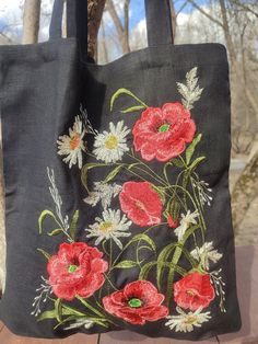 a black bag with red and white flowers on it sitting on top of a wooden table