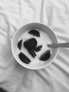 a bowl filled with oreos and milk on top of a bed covered in white sheets