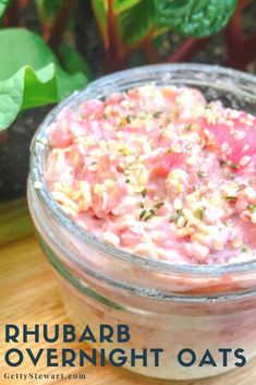 a jar filled with food sitting on top of a wooden table next to green plants