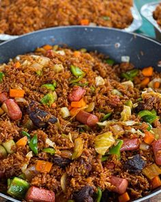 a pan filled with rice and vegetables on top of a table next to other dishes