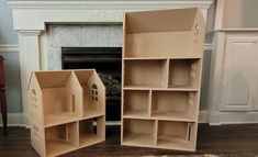 two cardboard doll houses sitting next to each other on the floor in front of a fireplace