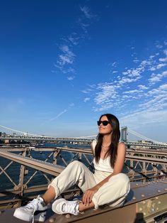 a woman sitting on top of a bridge next to the water