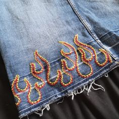 a pair of jeans with embroidered snakes on them