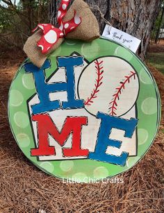 a wooden sign that says home with baseballs on it and a bow tied to the front