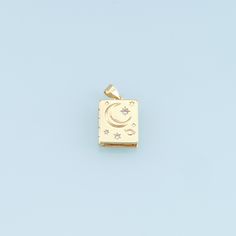 a gold charm with the moon and stars on it, against a light blue background