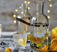 two bottles filled with liquid next to some oranges and an empty glass on a table