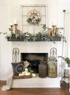 a fireplace with candles, pumpkins and greenery on the mantel above it