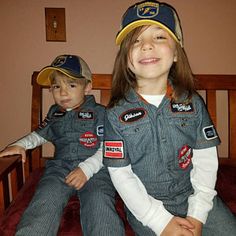 two young boys sitting on top of a bed wearing matching outfits and hats with patches