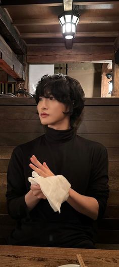 a woman sitting at a table with her hands folded