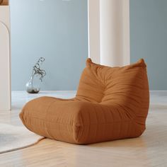 a brown bean bag chair sitting on top of a hard wood floor next to a vase