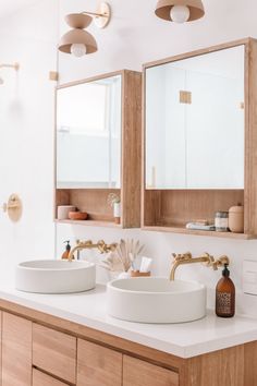 a bathroom with two sinks and mirrors in the wall above it is also a large mirror