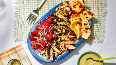 a blue plate topped with chicken and veggies next to a bowl of sauce