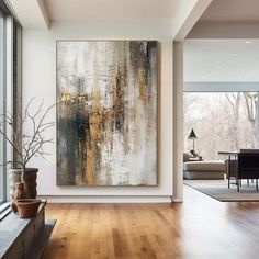 an abstract painting hangs on the wall next to a window in a modern living room