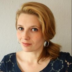 a woman with blonde hair is looking at the camera and has big earrings on her head