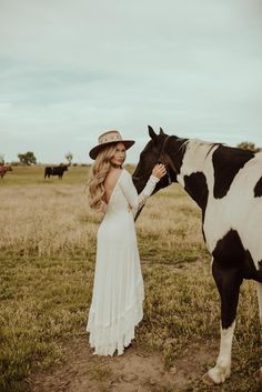 a woman standing next to a black and white horse