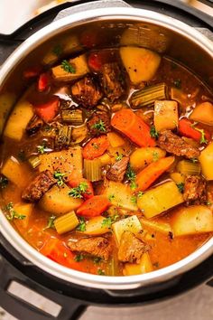 a pot full of stew with carrots, potatoes and meat in it on the stove