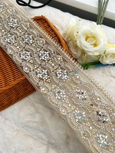 two pieces of beaded fabric next to a basket with flowers