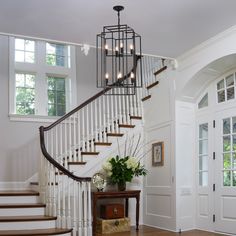 a foyer with white walls and wooden flooring next to a stair case filled with flowers