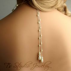 the back of a woman's head wearing a necklace with two blue stones on it