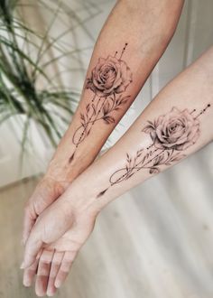 two people holding hands with tattoos on their arms and one is holding the other's hand