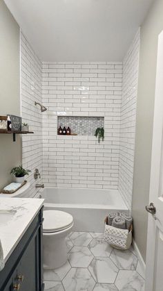 a bathroom with white tile and hexagonal tiles on the floor, along with gray cabinets