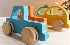 two wooden toy cars sitting next to each other on a white counter top with a christmas tree in the background